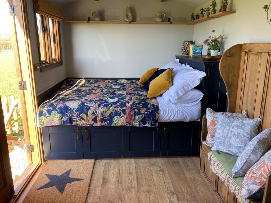 Inside the hut is white walls with a black cabin style bed and upcycled wooden seat