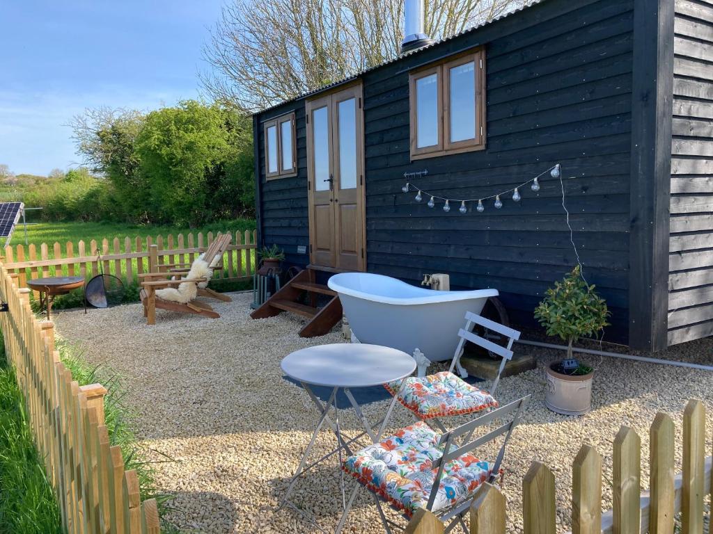 The quaint Marsh Farm shepherds hut with out door hot tub. The hut is wooden and painted black with brown windows