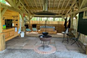 An outdoor covered area with a fire pit and outdoor kitchen