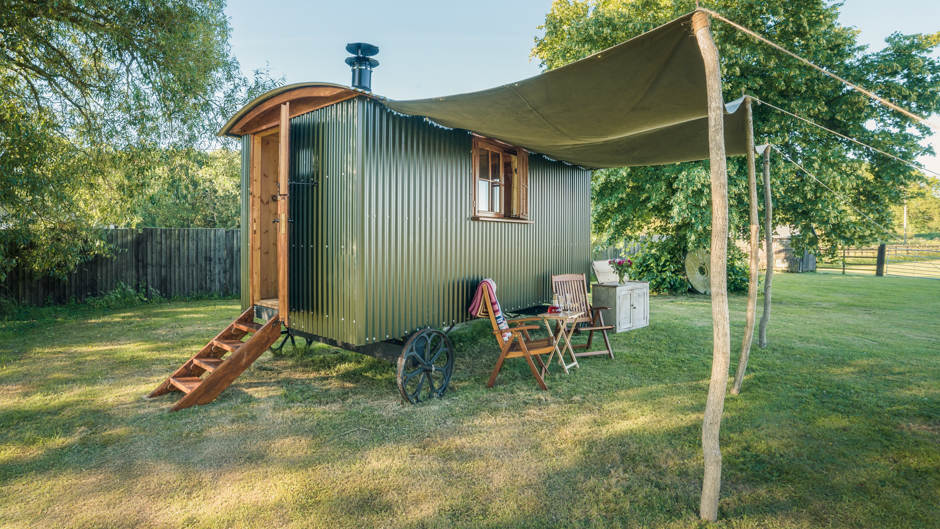 Longwool shepherds hut - a traditional metal shepherds hut on wheels with covered awning to the side